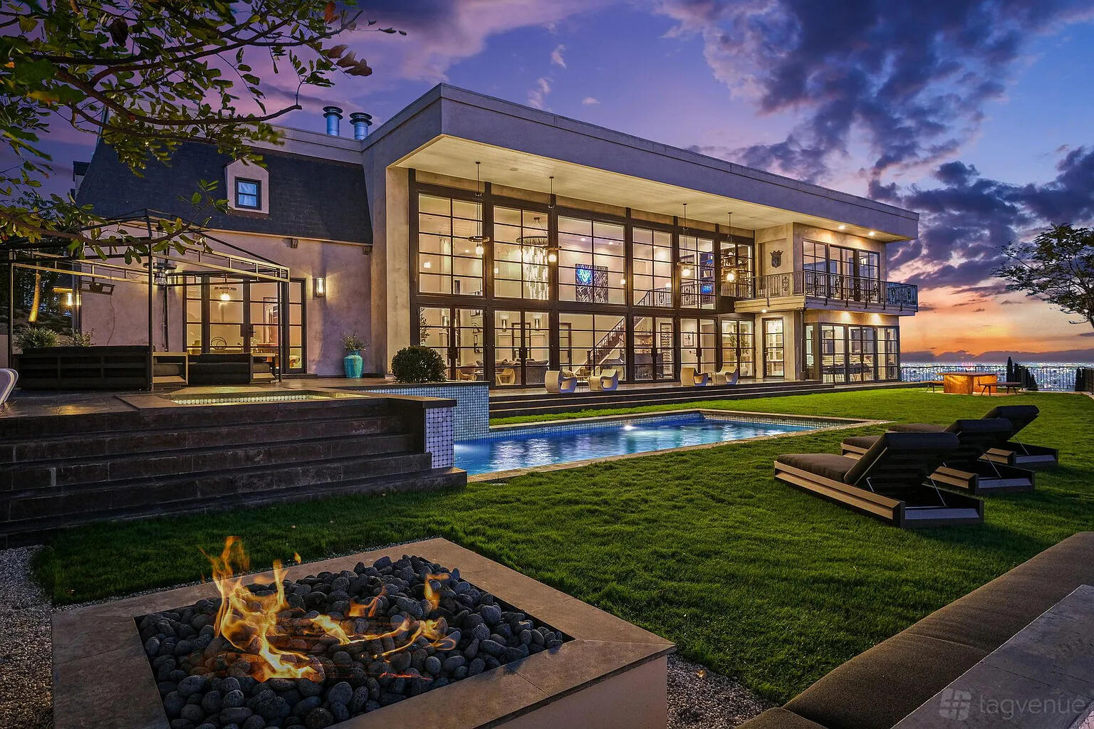 An apartment with floor-to-ceiling windows, outdoor pool, lounge chairs, and a fire pit at Sophisticated Estate with Views.