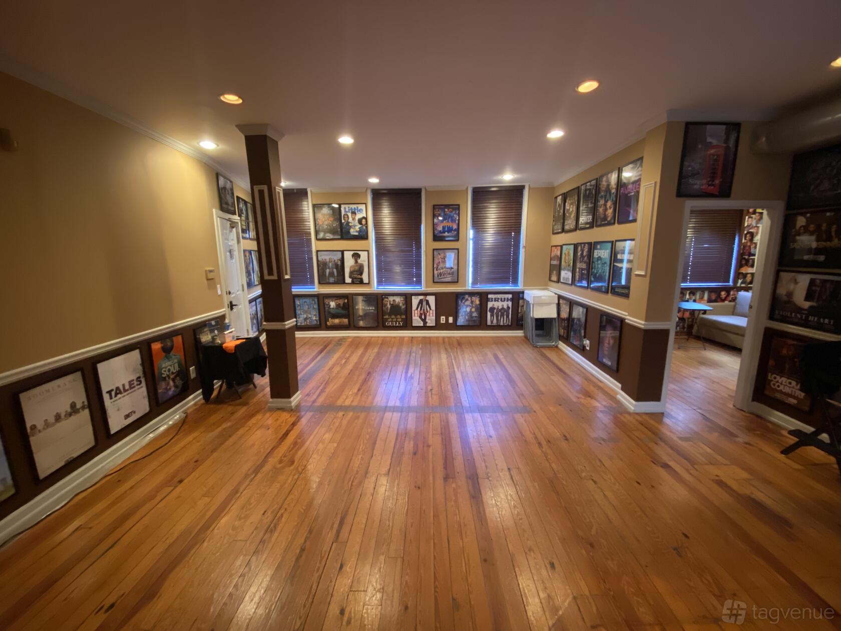An art studio with polished wood floors, framed posters on tan walls, and recessed ceiling lights at LS ACTING STUDIOS.