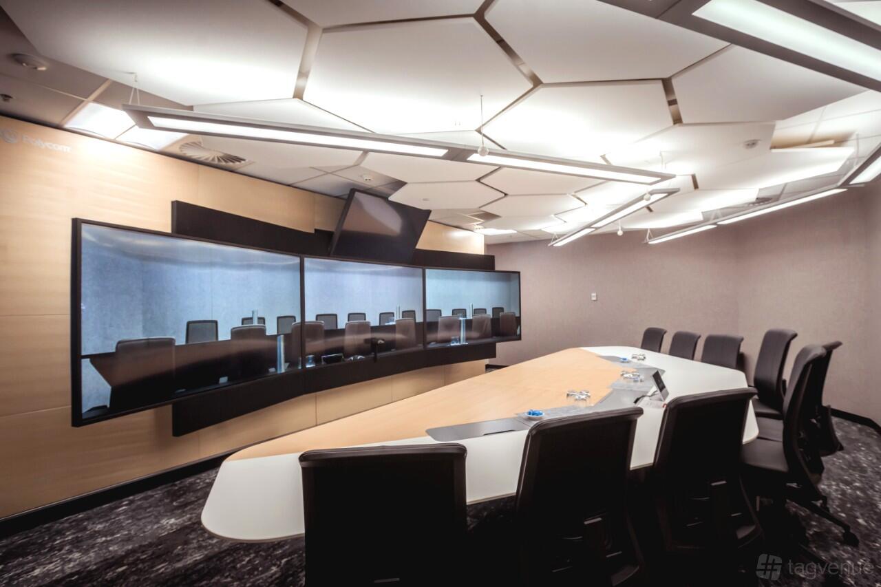 A meeting room with a long conference table, multiple chairs, large video screens, and geometric ceiling lights at Dexus Place St Georges Terrace.