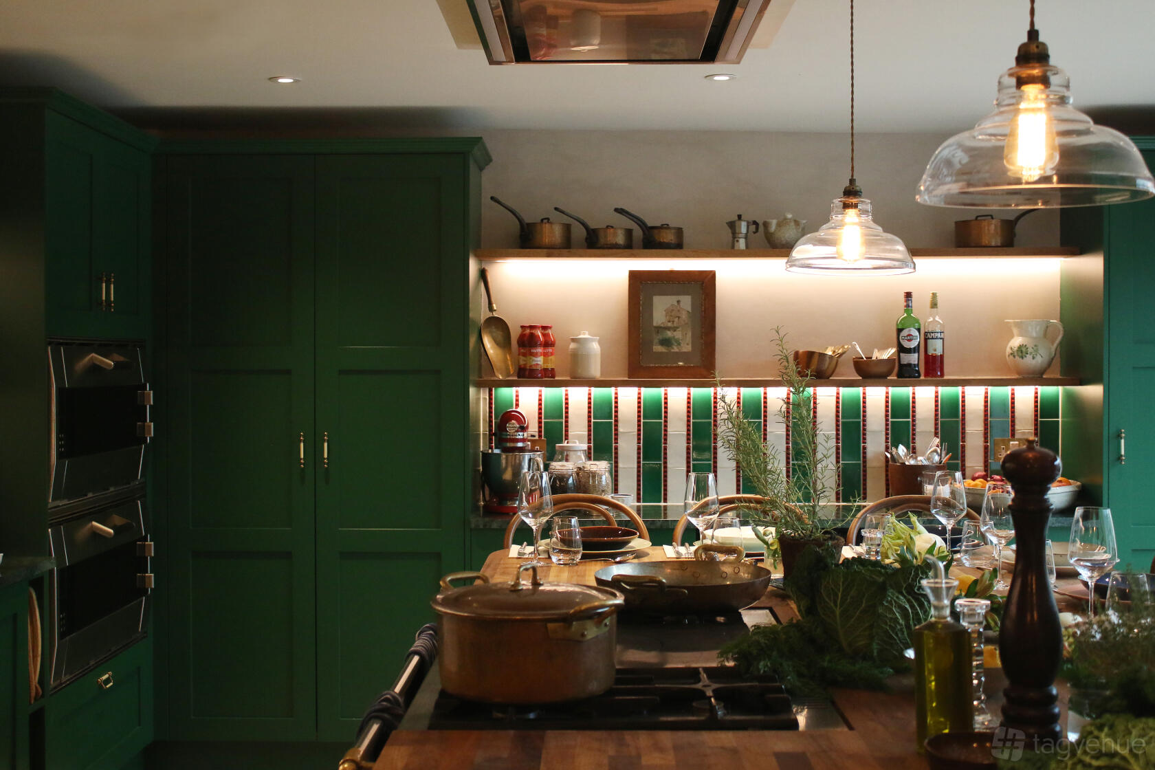 A kitchen with green cabinetry, open shelving with cooking essentials, and a central island at Enrica Rocca Cookery School And Events Space.