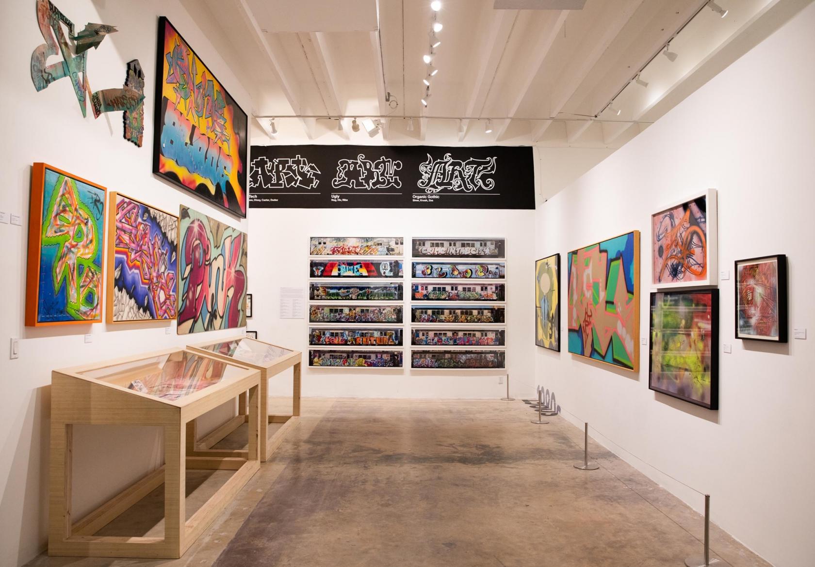 A contemporary art gallery with graffiti murals, framed artwork, and display cases at Museum of Graffiti.