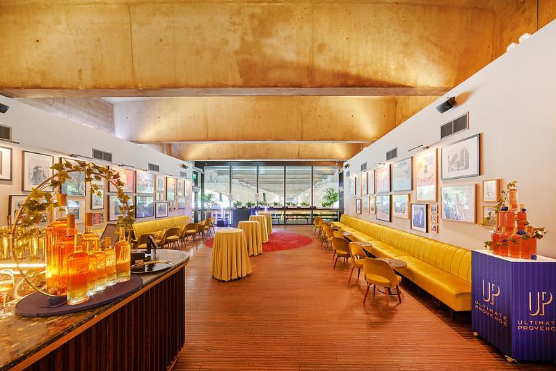 An event space with a yellow banquette, framed art on white walls, and floor-to-ceiling windows at Benugo @ The BFI Southbank.