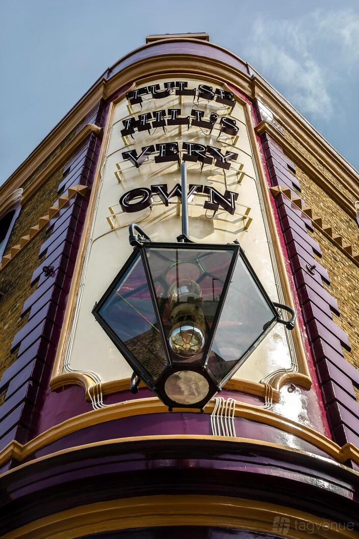 A pub with exposed brick exterior, maroon trim, and a large lantern hanging above the entrance at Queen of the South.