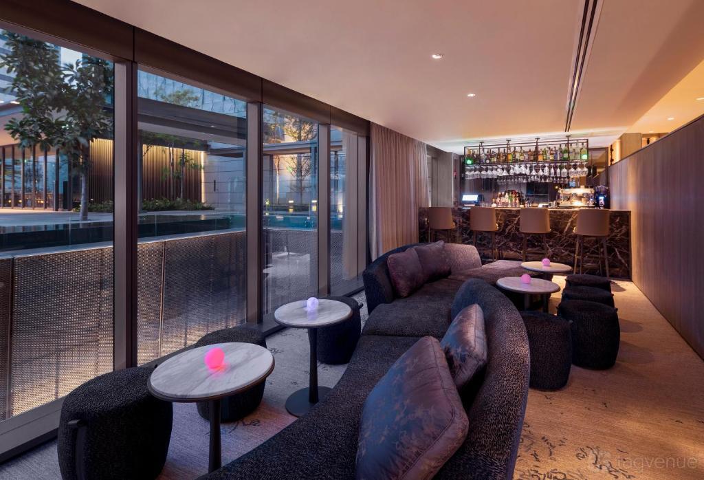 A hotel bar with floor-to-ceiling windows, plush curved sofas, and a backlit counter at Dao by Dorsett AMTD Singapore.