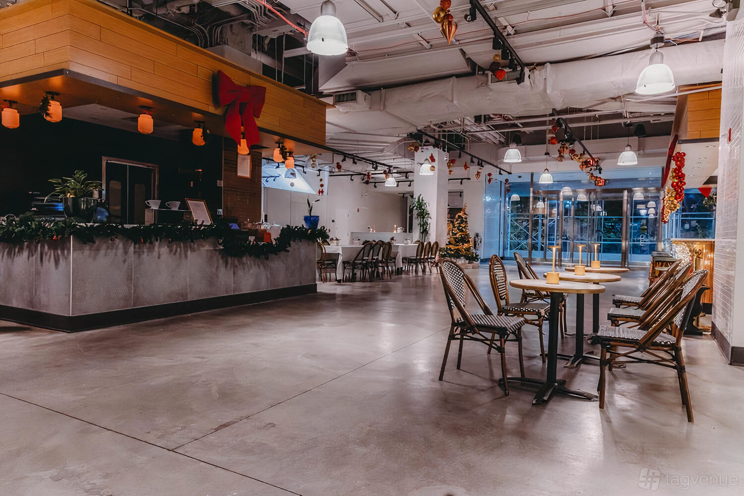 An event space in a restaurant with bistro chairs, small tables, and festive garlands at Le District.