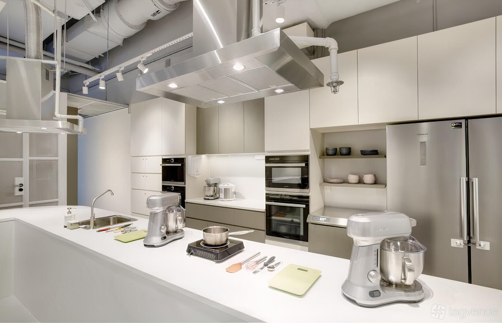A commercial kitchen with stainless steel appliances, induction cooktops, and built-in ovens at IncuBaker.