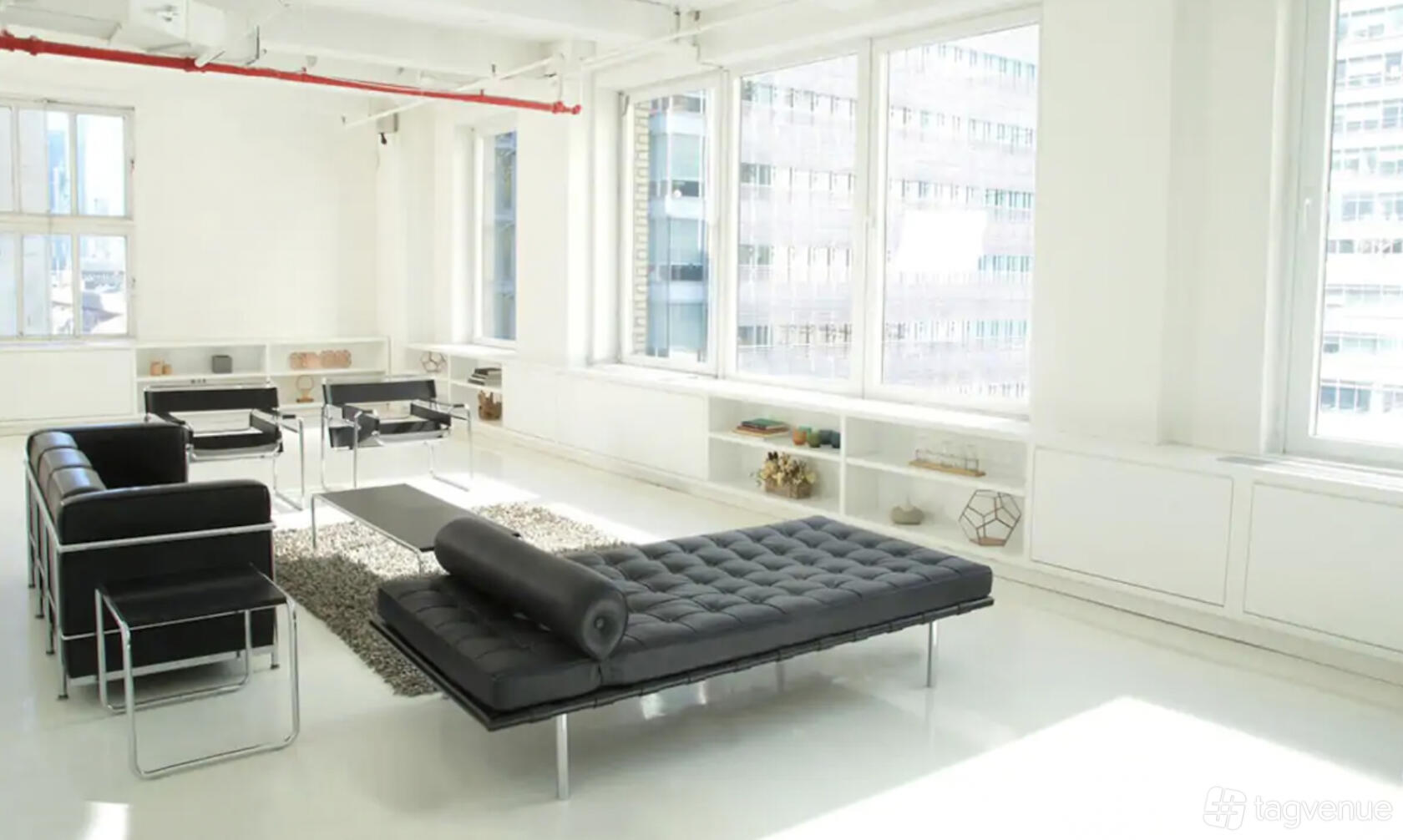 A photo studio with large windows, black leather seating, and white floors at Studio 250.