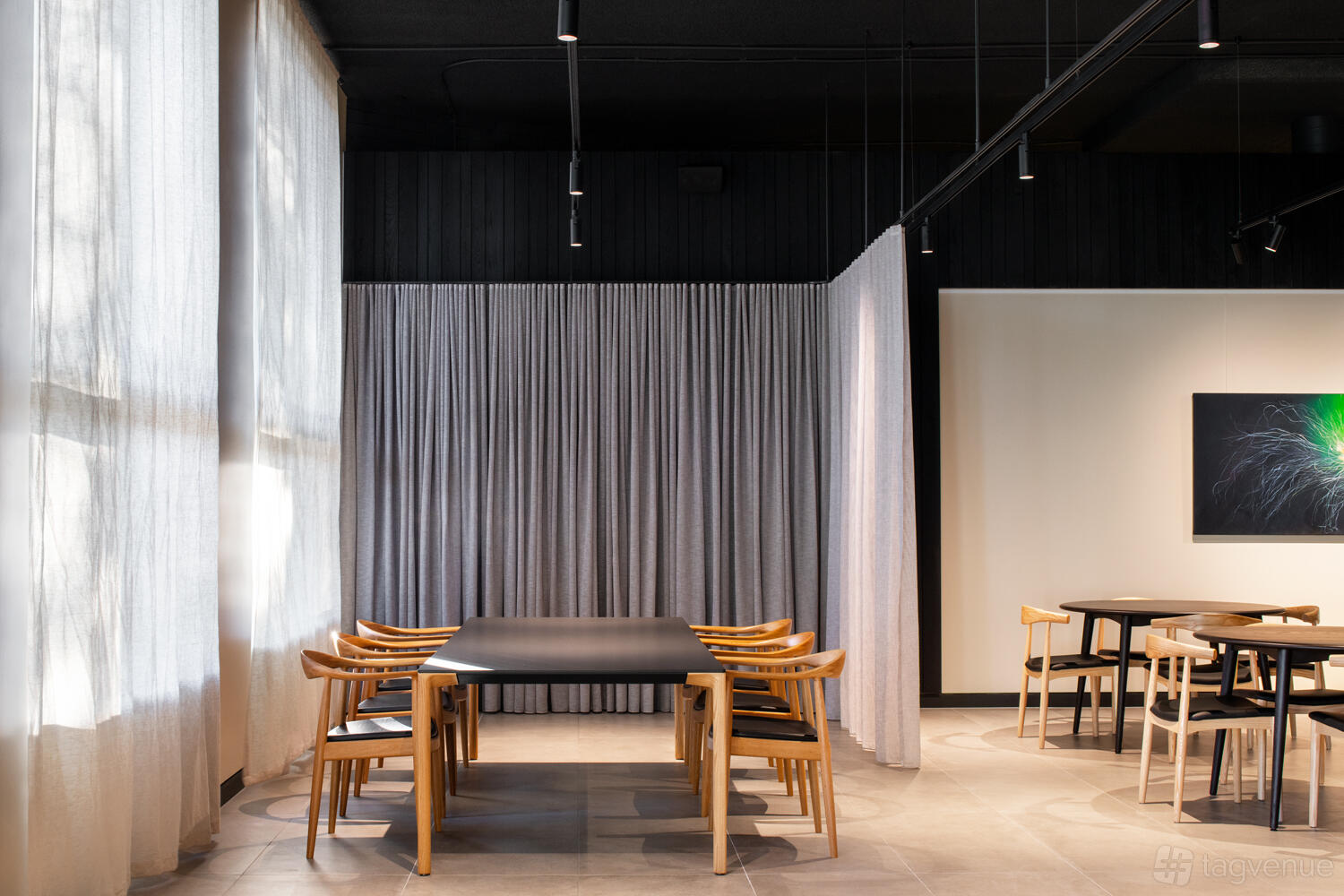 A private dining room with a long black table, wooden chairs, floor-to-ceiling curtains, and soft natural lighting at KOMEYUI Melbourne.