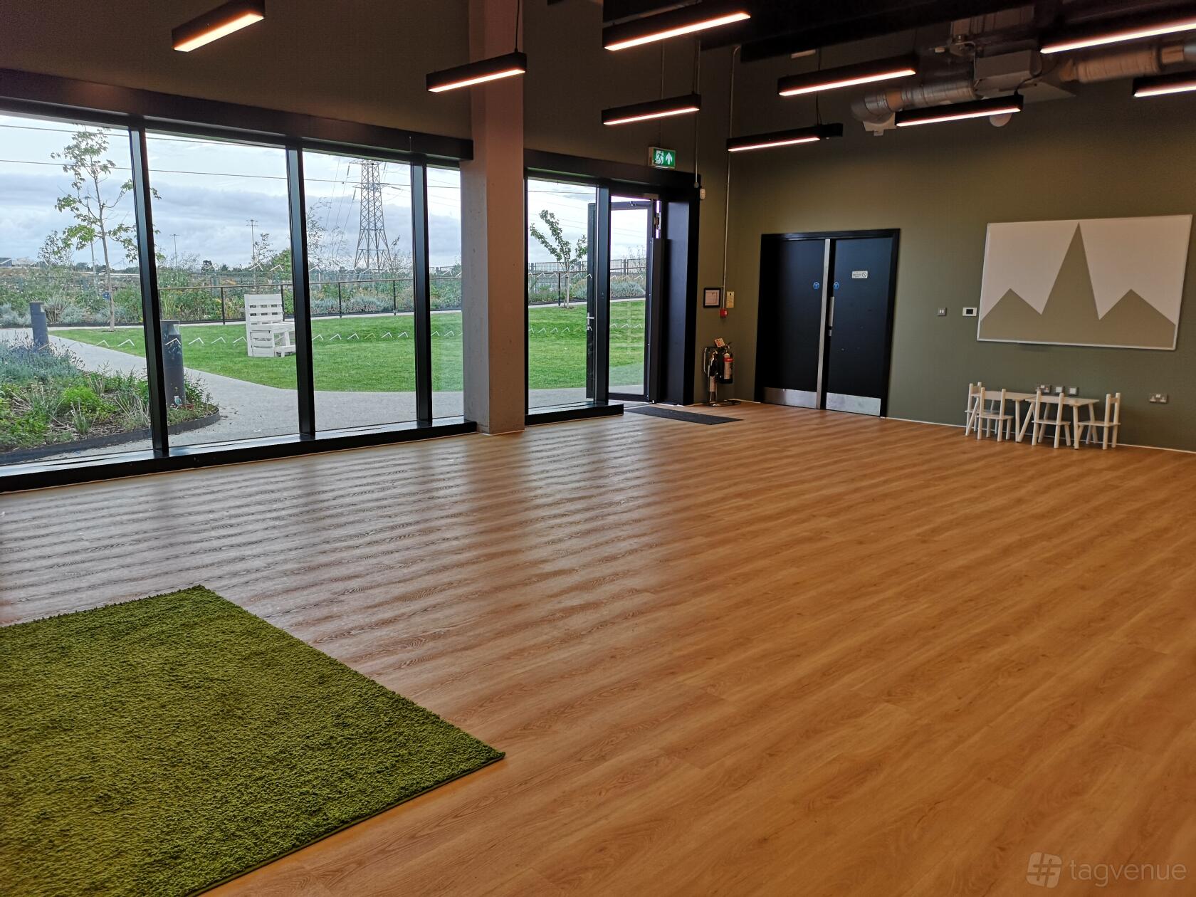 An event venue with floor-to-ceiling windows, wood flooring, and green garden views at The Wilds.