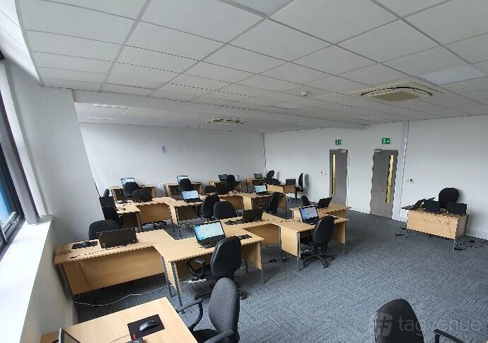 A training room with rows of desks, office chairs, and laptops at ITTS.