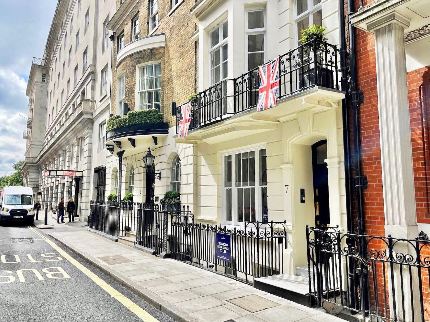 A coworking space with cream-colored townhouse facade, wrought iron railings, and balconies at 7 Stratton Street.