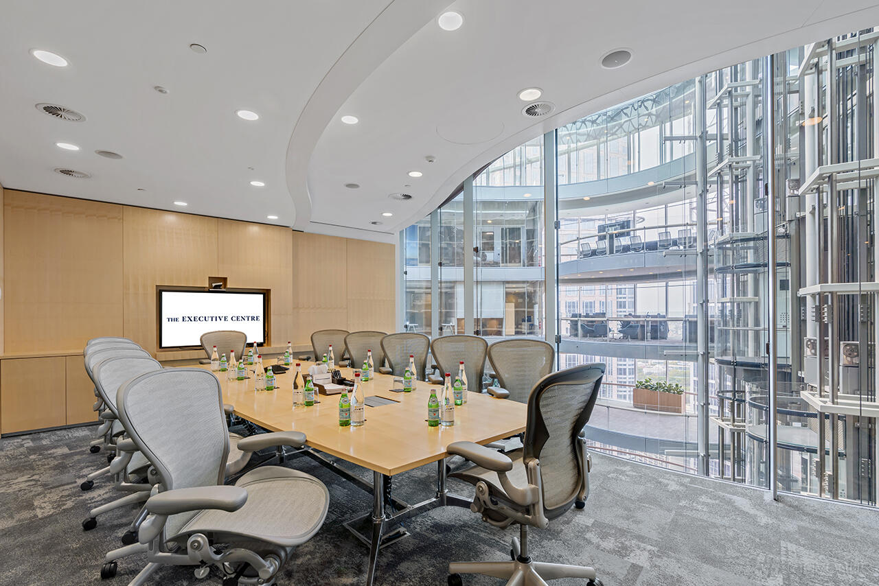 A boardroom with a long conference table, ergonomic chairs, floor-to-ceiling windows, and water bottles at 1 Bligh Street.