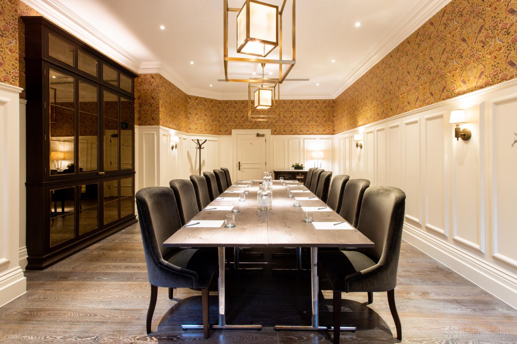 A meeting room with a long wooden table, high-back chairs, and patterned wallpaper at Kimpton Fitzroy London.