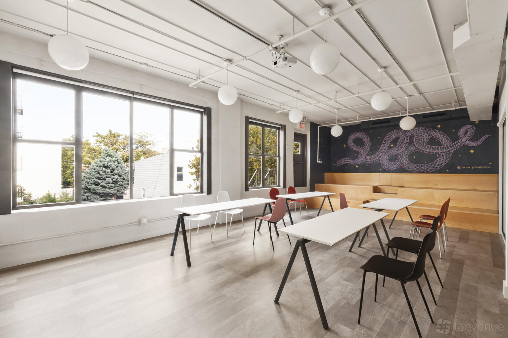 An event space with modular tables, mixed chairs, large windows, and a mural wall at CLASS & CO.