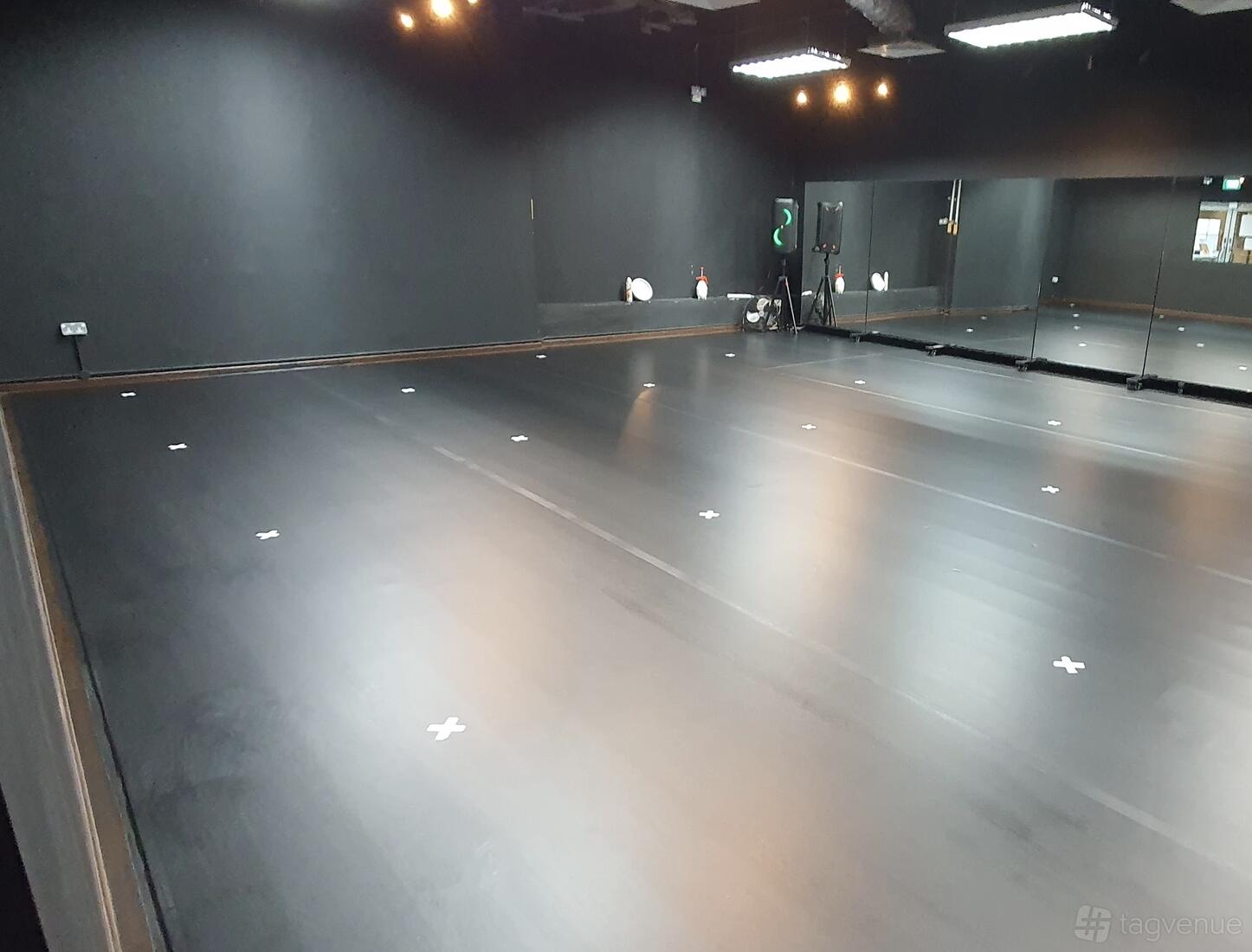 A dance studio with black floors, wall-length mirrors, and white floor markers at Converge Studios Potong Pasir.