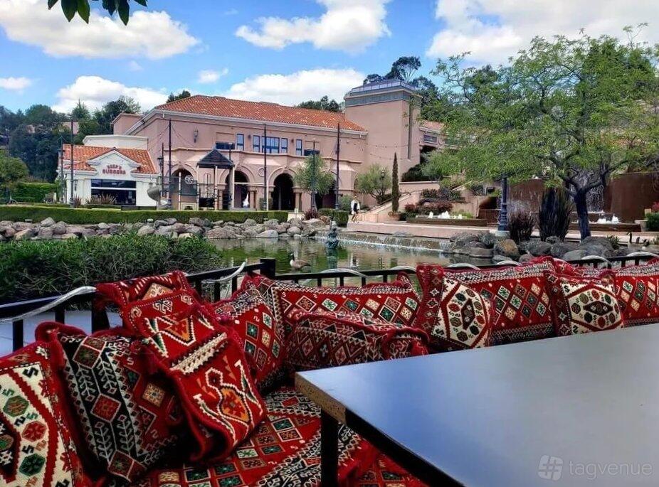 An outdoor restaurant patio with patterned cushioned seating by a pond at 786 Kabob House.