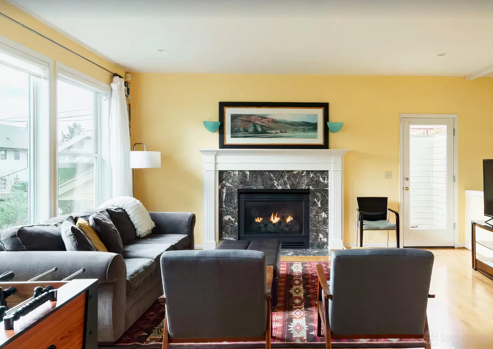 An apartment living room with a marble fireplace, large windows, and cozy seating at Delightful Ocean View Retreat Home.