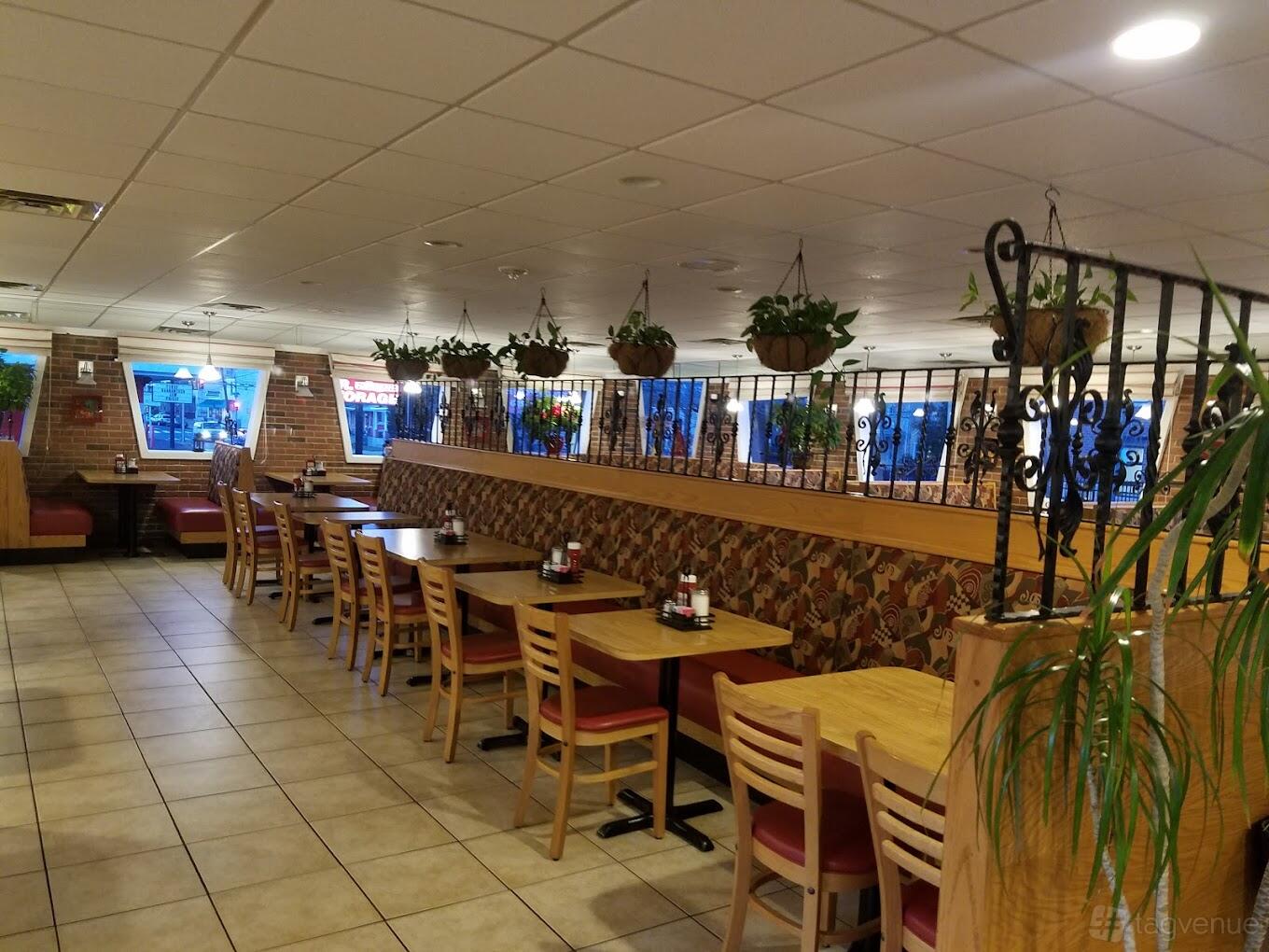 A restaurant dining area with tiled floors, wooden tables, cushioned booths, and hanging plants at Daiva's Grille.