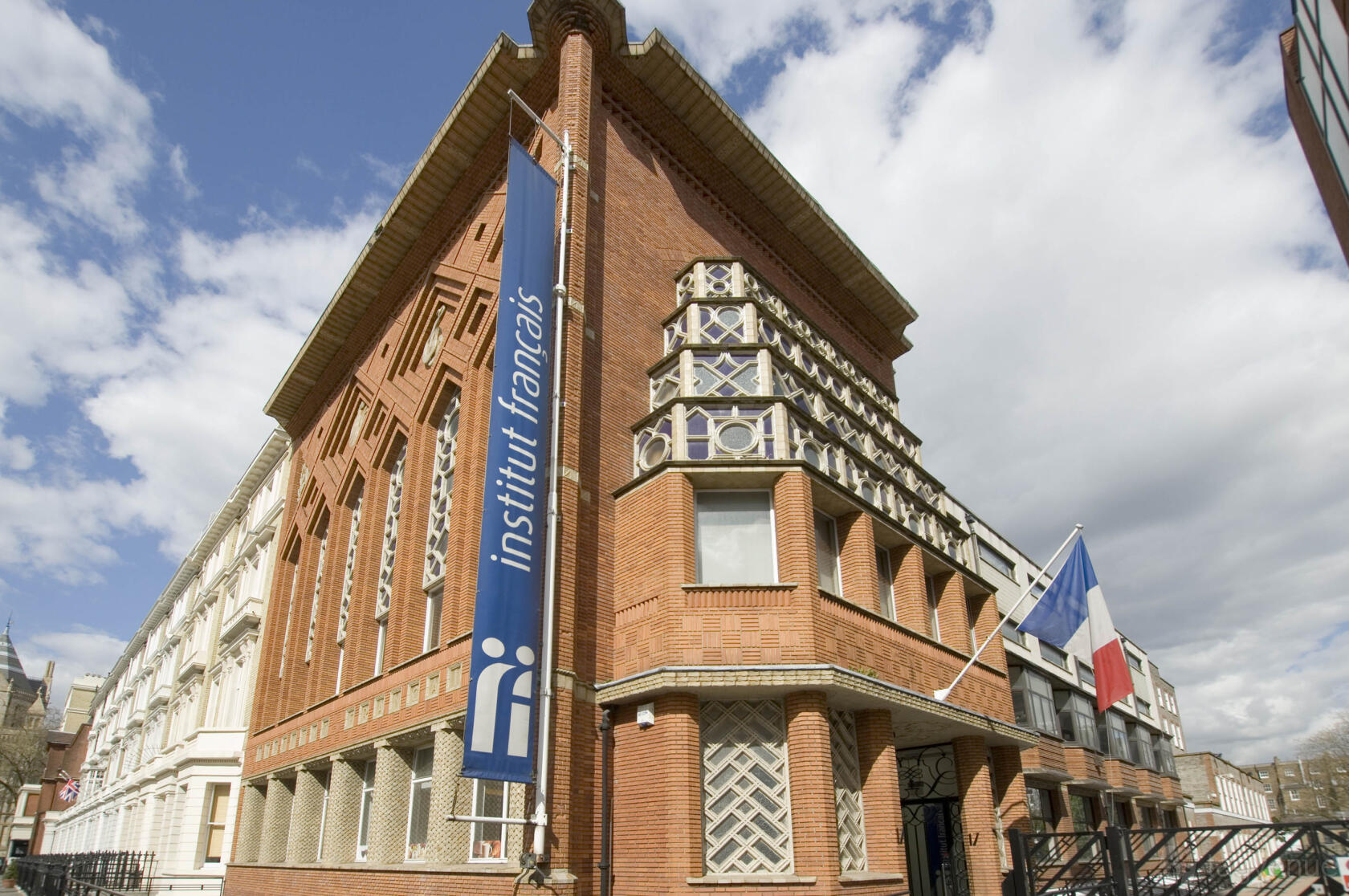 A historic building with red brick facade, geometric patterns, and French flag at Institut français au Royaume-Uni.