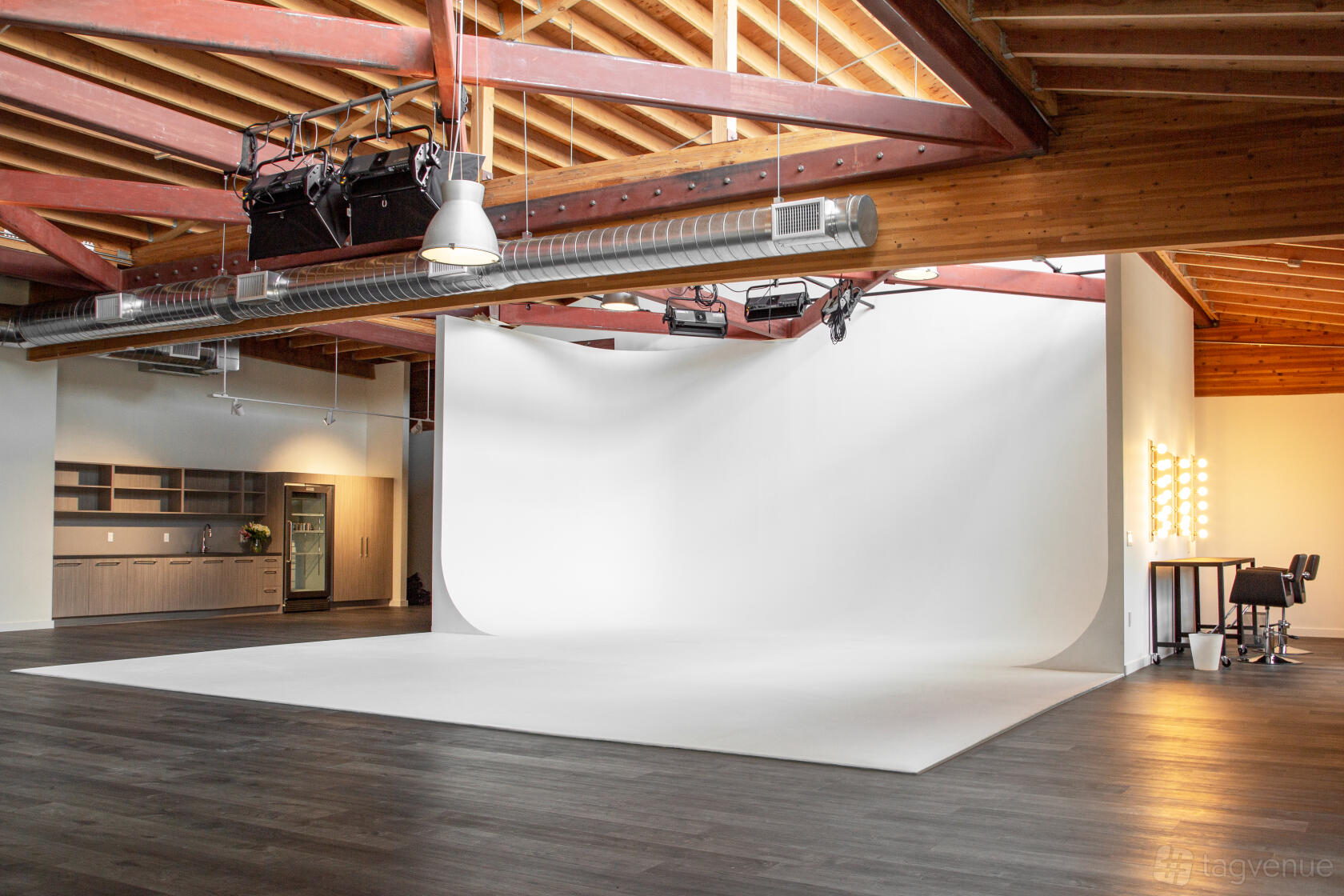 A photo and film studio with a prelit white cyclorama wall, exposed beam ceiling, and makeup station at Eastbound Studio.