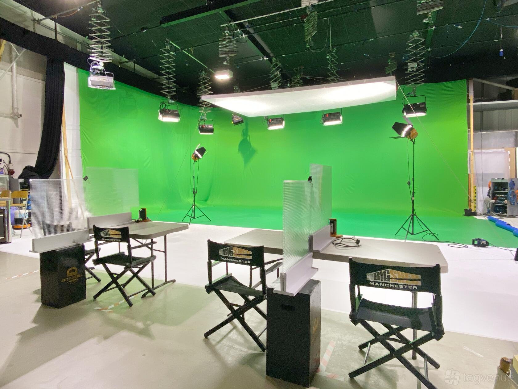 A photo studio with a large green screen backdrop, overhead lighting, and director chairs at Big Shed Film & Photographic Studio.