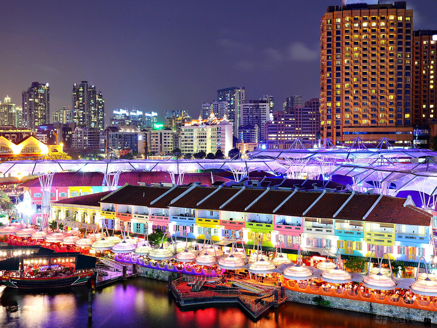 An exterior view of the meeting centre with colorful waterfront buildings and city skyline lights at HUONE Singapore.