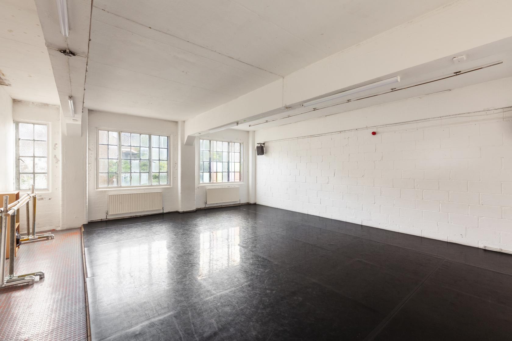A rehearsal room with a sprung dance floor, large windows, and ballet barres at Chisenhale Dance Space.