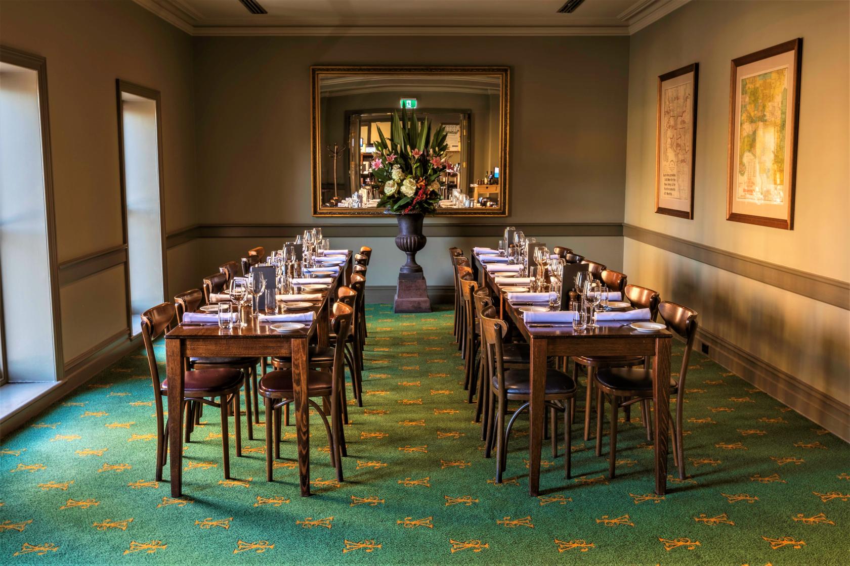 An event space in a pub with two long tables set with glassware and a large floral arrangement at Young & Jacksons.