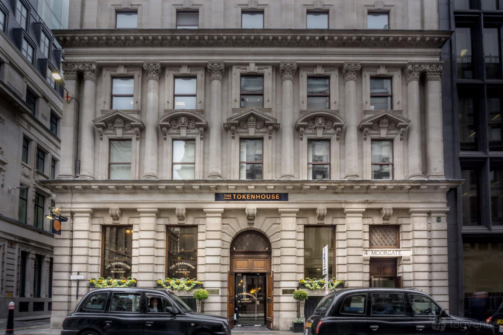 A pub with a grand stone façade, arched windows, and decorative columns at Tokenhouse.