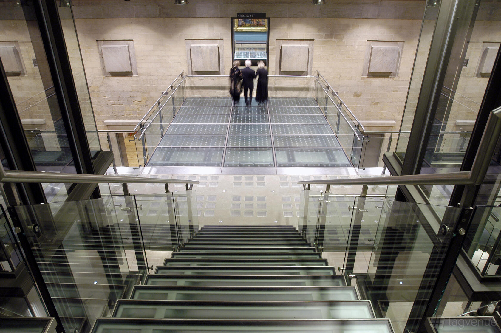 An event space in a gallery with a glass staircase, glass floors, and exposed brick walls at Manchester Art Gallery.