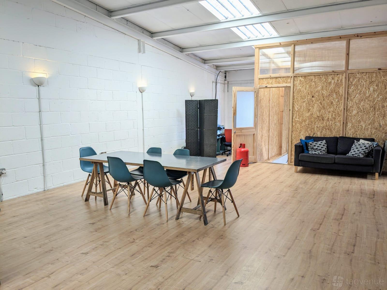 A meeting room with a long table, black chairs, sofa seating, and plywood walls at Canababes Food Co.