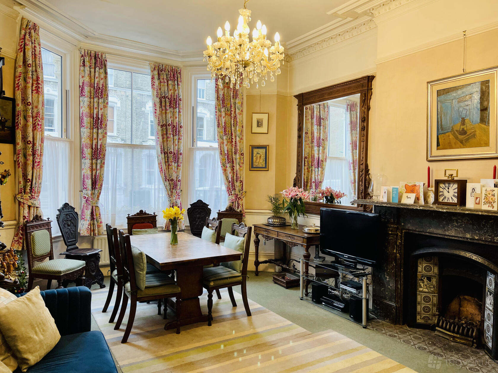 A photo studio in a Victorian living room with tall windows, floral curtains, chandelier, and antique furniture at Sinclair Studio Spaces.