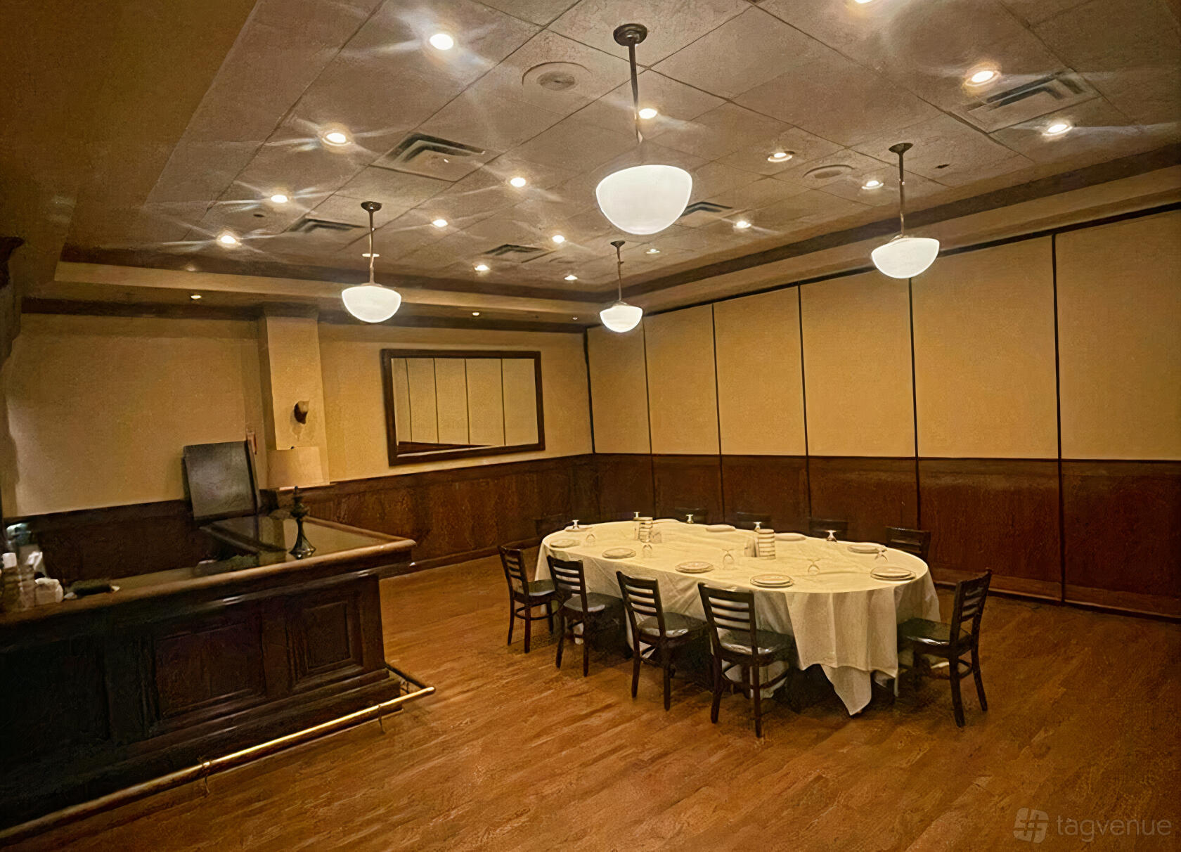 A dining room with a round table set with white linens, wood-paneled walls, and pendant lighting at Maggiano's Little Italy Chevy Chase.