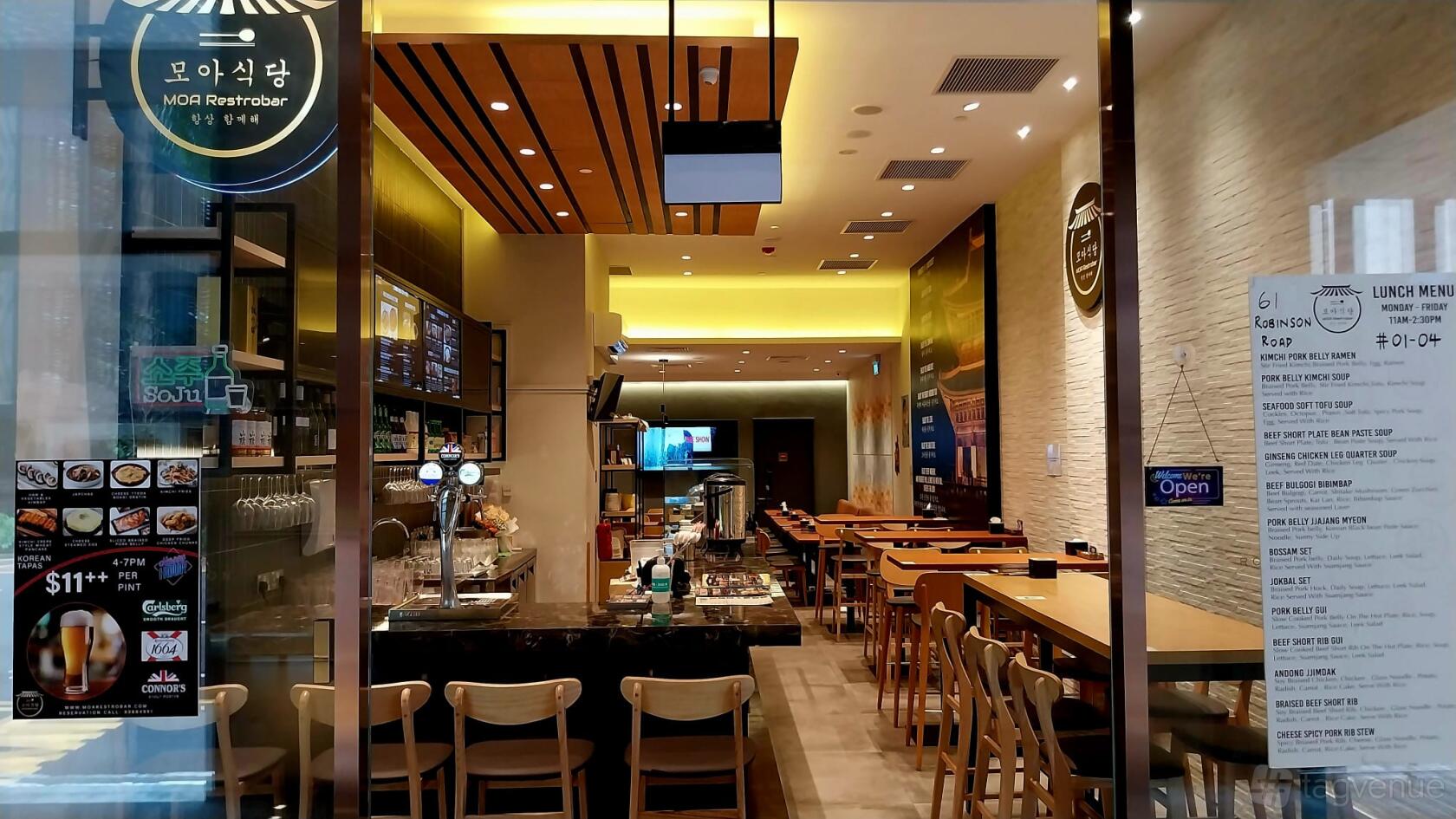 A restaurant with wood-accented ceiling, a marble-topped bar, and wooden tables with chairs at MOA RESTROBAR.