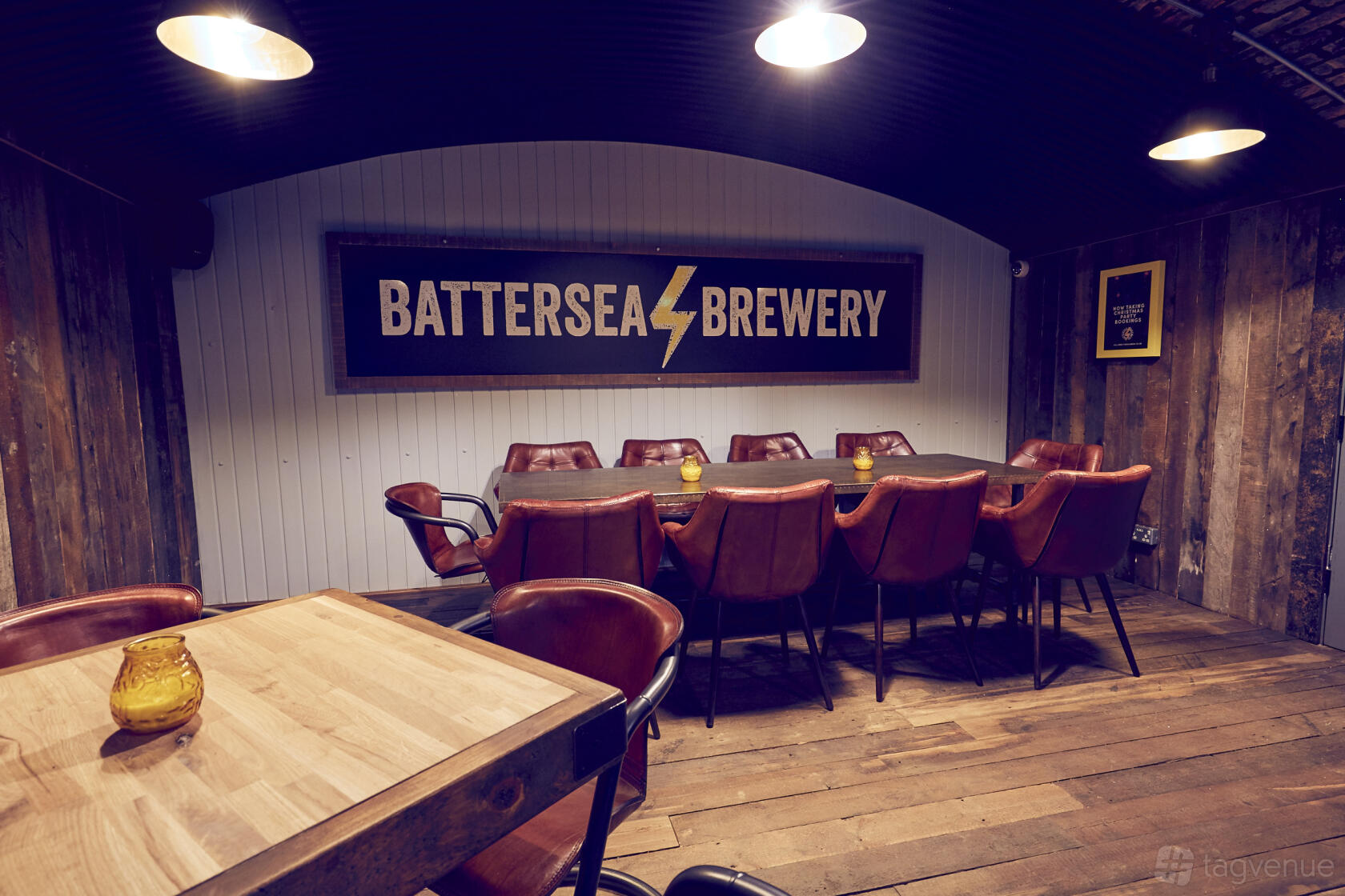 A pub dining room with leather chairs, wood-paneled walls, and a Battersea Brewery sign behind a long table