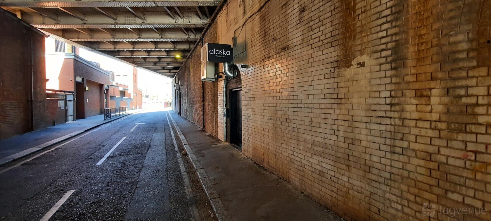 An entrance to a nightclub under a brick railway arch with a black sign reading 'alaska' at Alaska Waterloo.