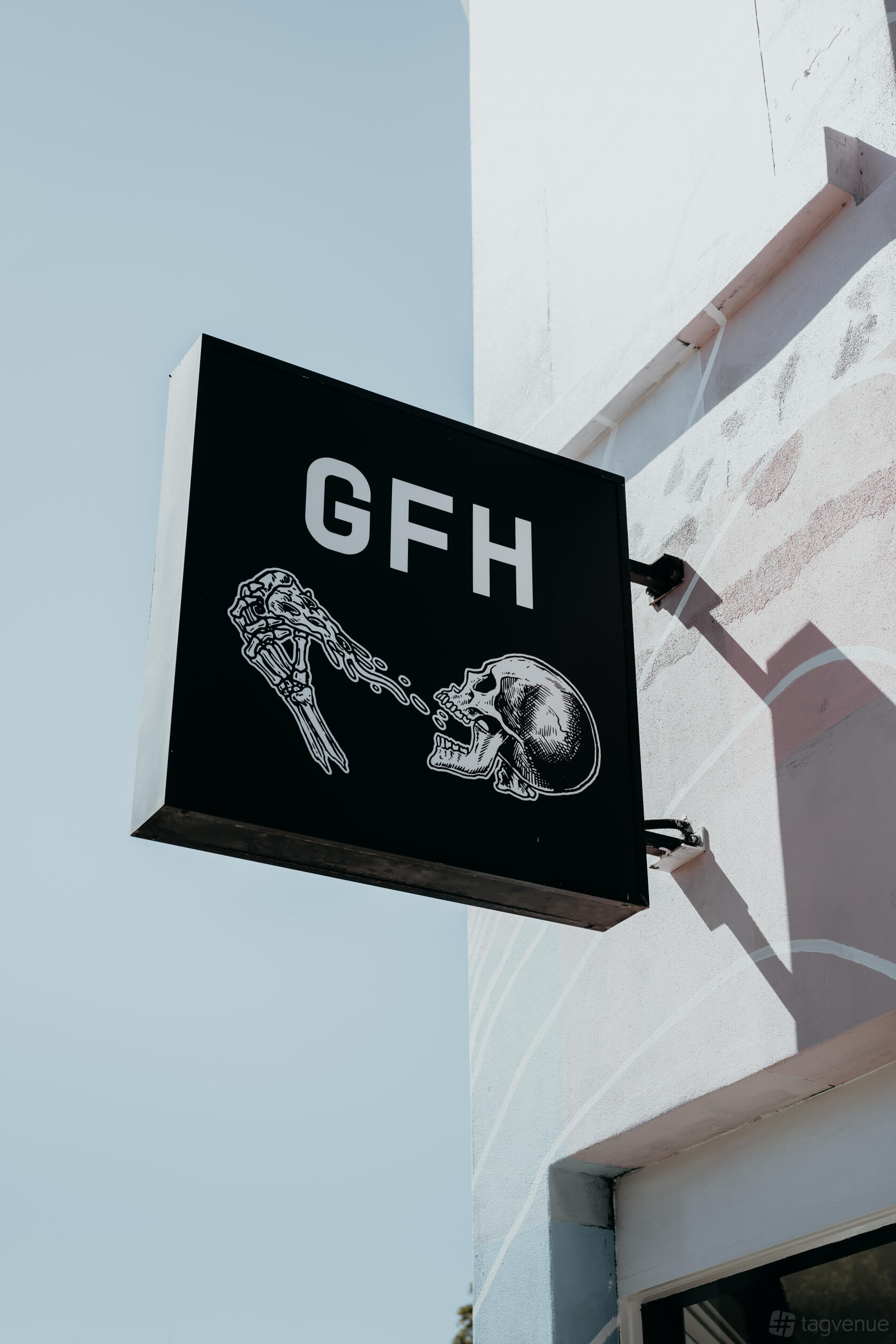 A restaurant sign with skeletal hand and skull artwork outside The Golden Fleece Hotel.