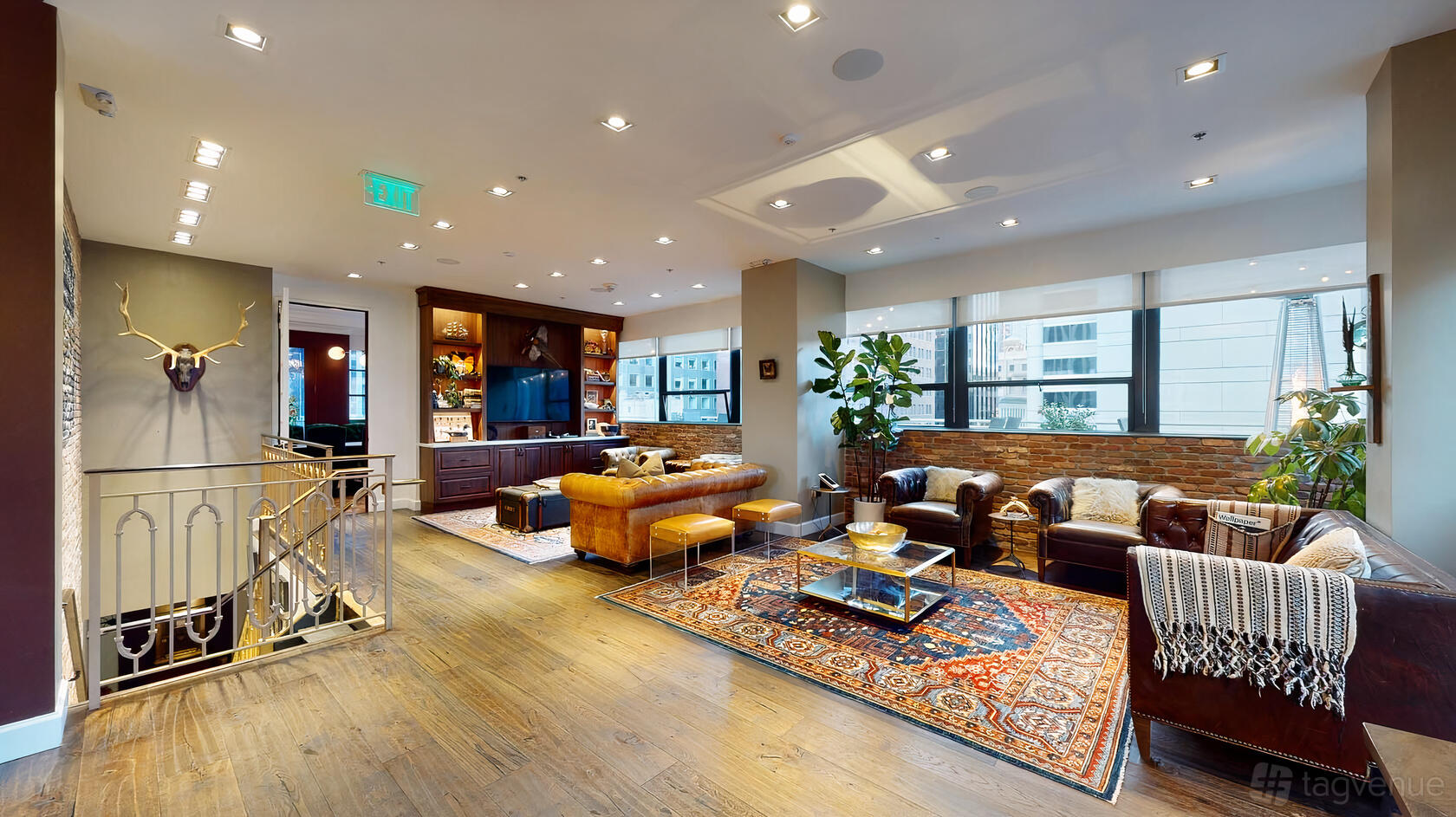 A penthouse event venue with floor-to-ceiling windows, leather seating, and patterned rugs at The Newhall Nest.