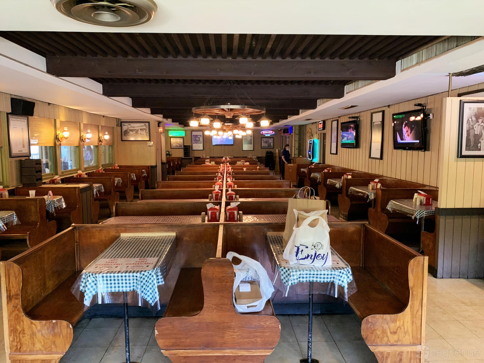 A restaurant event space with wooden booths, checkered tablecloths, and wall-mounted lighting at Russell's Barbecue.