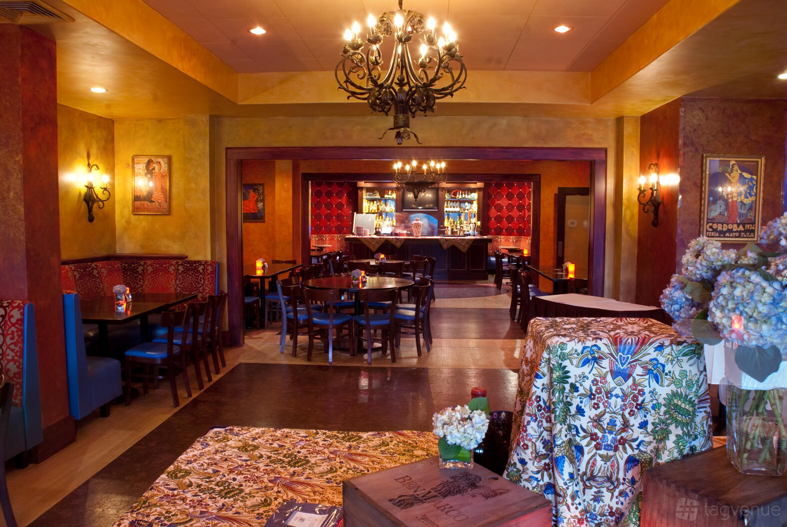 A restaurant with chandeliers, patterned tablecloths, and warm-toned walls at Solea Restaurant and Tapas Bar.