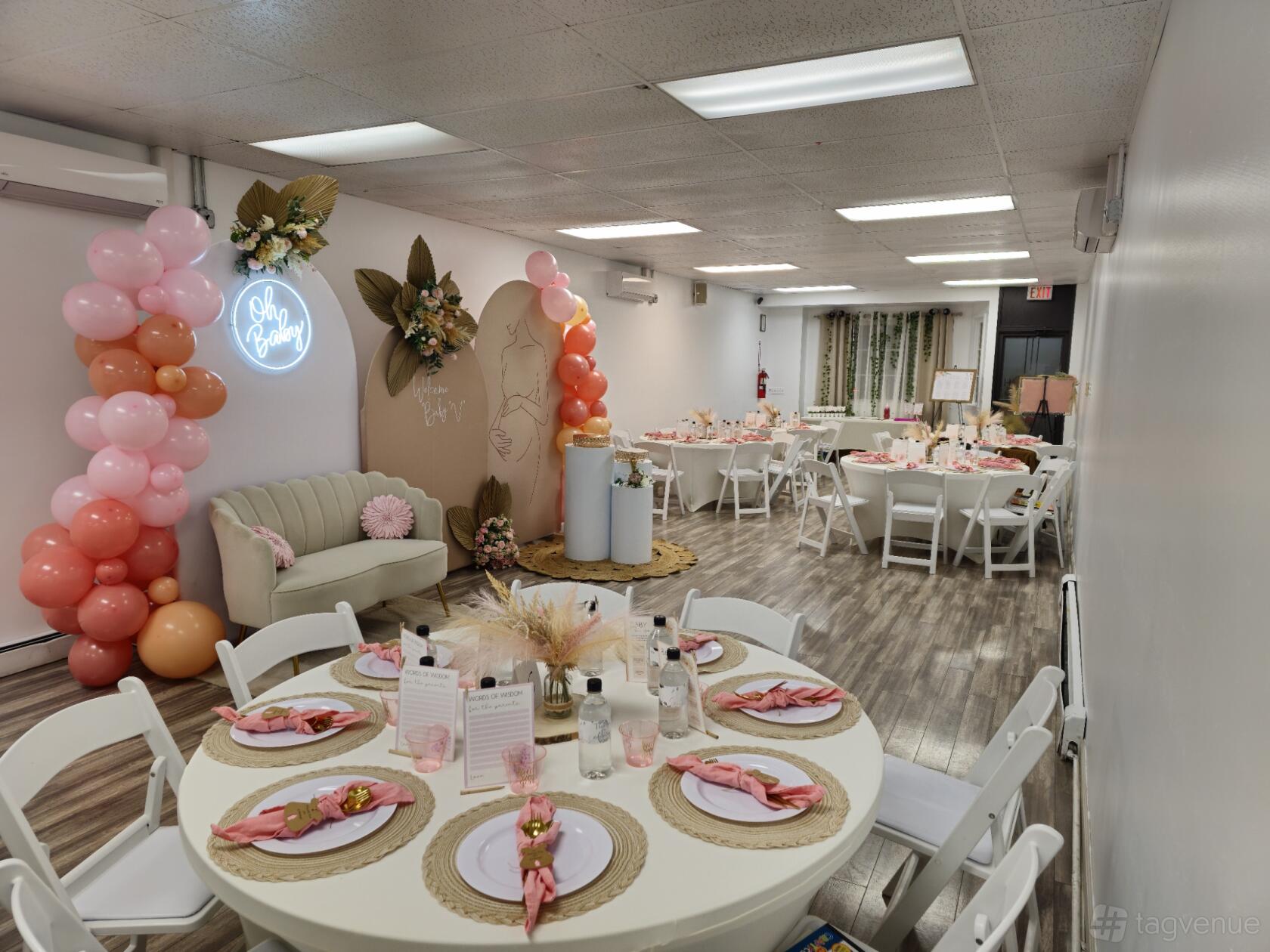 An event venue with round tables set with pink napkins, balloon decorations, and a neon sign at Zenith Events.