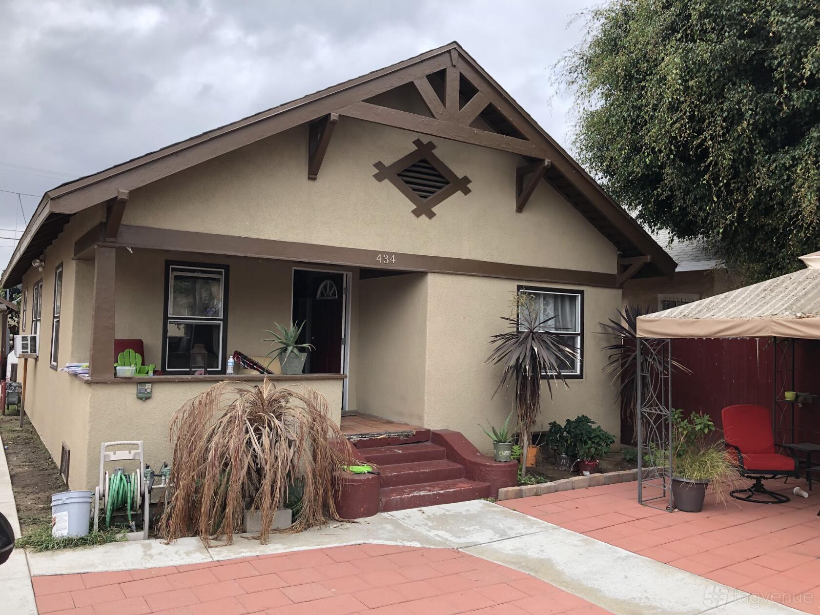 A film and photo studio with a beige bungalow exterior, small porch, and potted plants at 60th St. House
