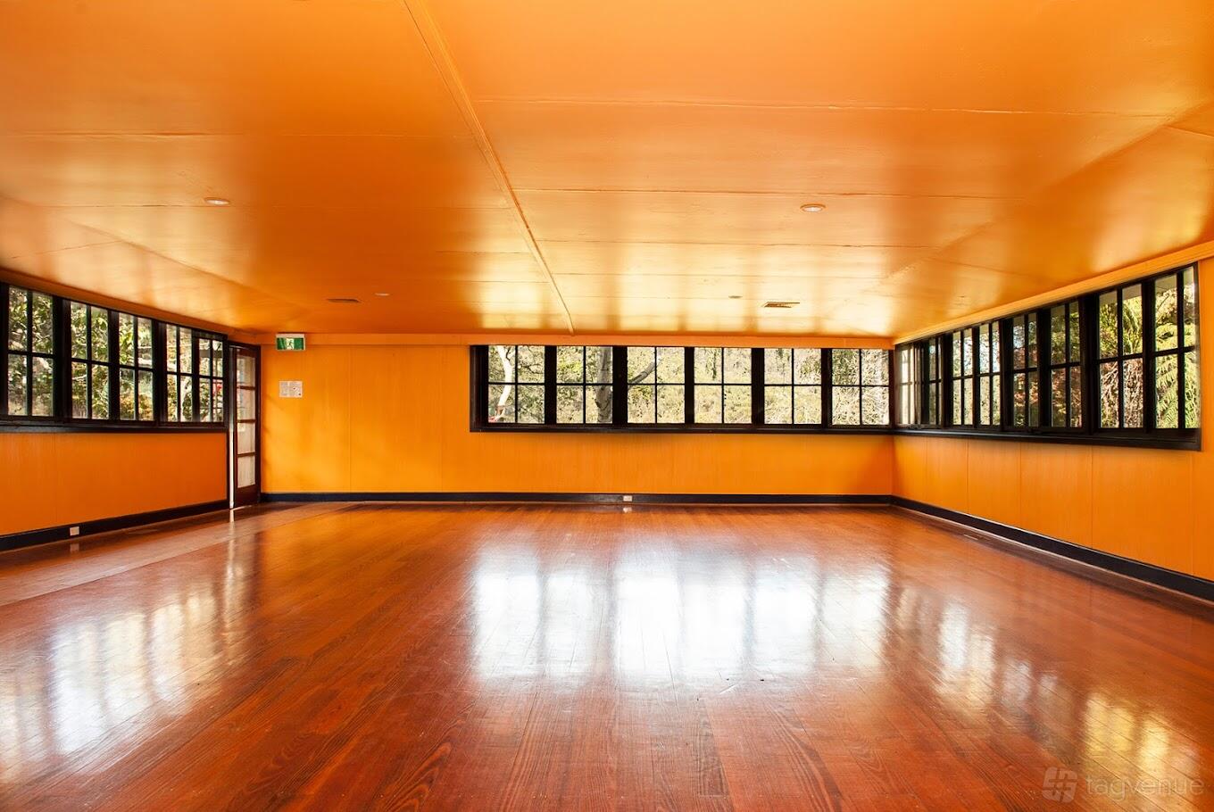 An event venue with polished wooden floors and large windows with black frames at Maitripa Centre.