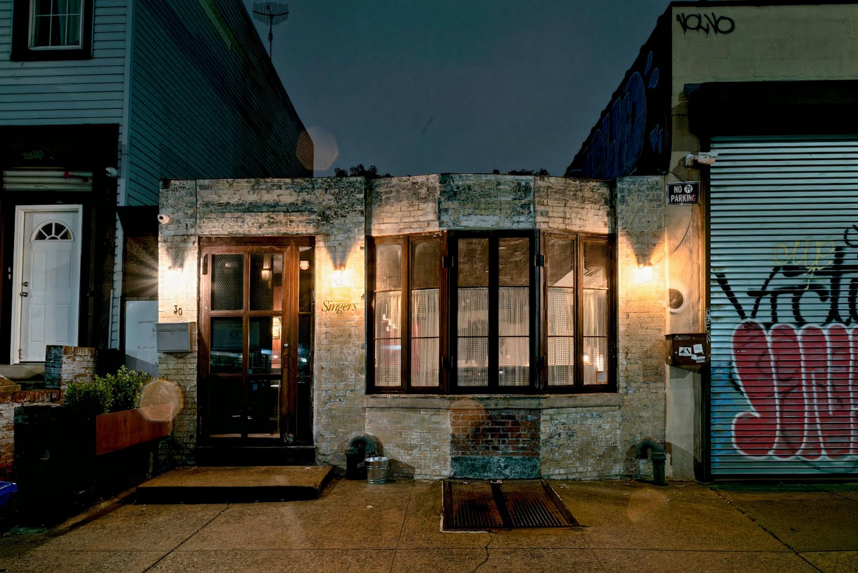 A pub with a brick facade, large bay window, and illuminated entrance at Singers.