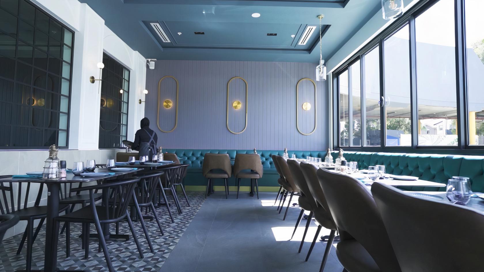 A restaurant with teal upholstered banquette seating, large windows, and geometric floor tiles at Lazeez Lebanese Cuisine.