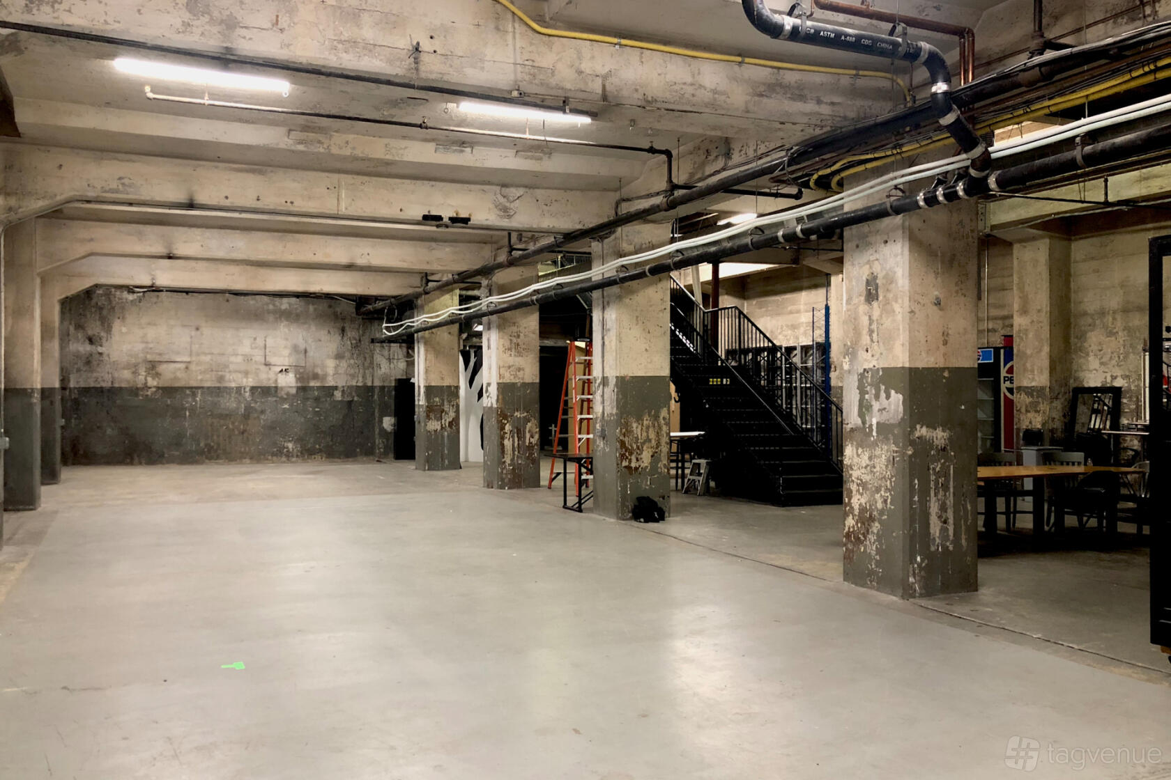 A photo studio with exposed concrete pillars, high ceilings, and industrial piping at Power Plant Productions Studio B.
