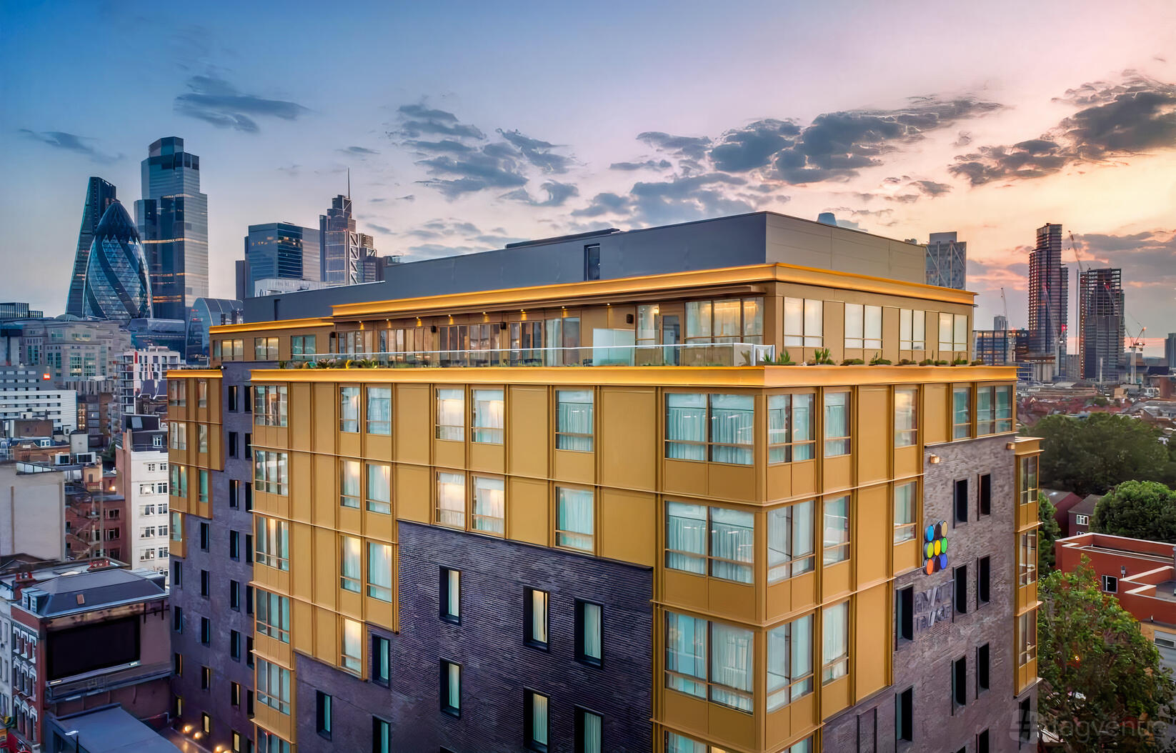 A multi-story restaurant with floor-to-ceiling windows and a wraparound terrace overlooking the London skyline at Hyatt Place London City East.