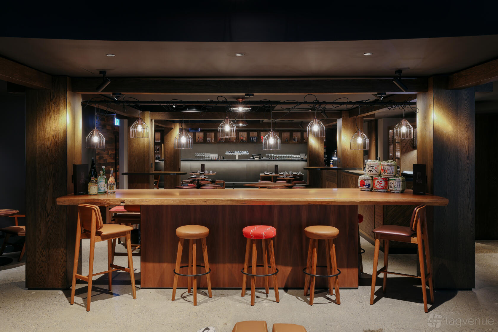 A hotel bar with pendant lighting, wooden high-top tables, and bar stools at Hotel Indigo Brisbane City Centre.