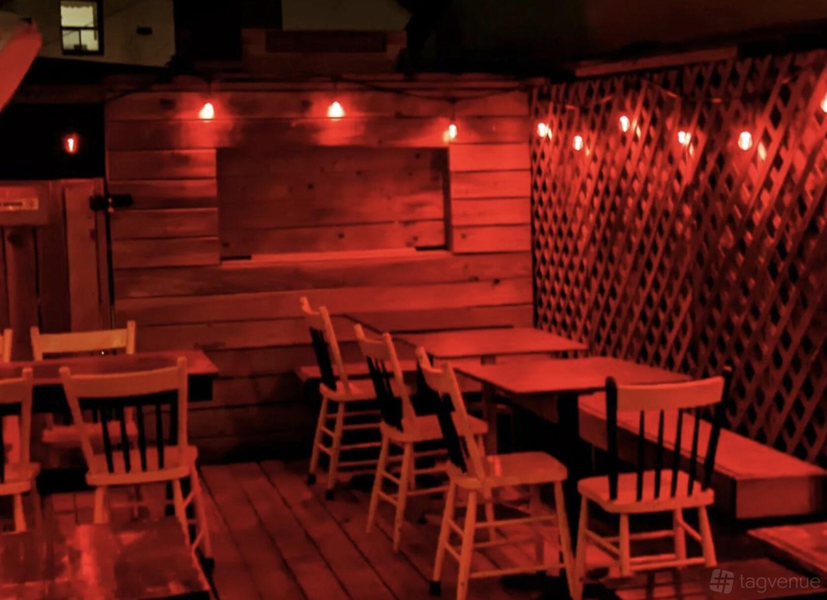 A bar patio with wood decking, lattice fencing, and string red lights at Wasted Youth Bar.