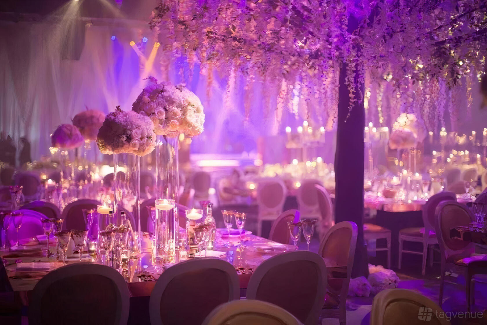 An event venue with purple lighting, floral centerpieces, and round tables set with glassware at Dunwoody.